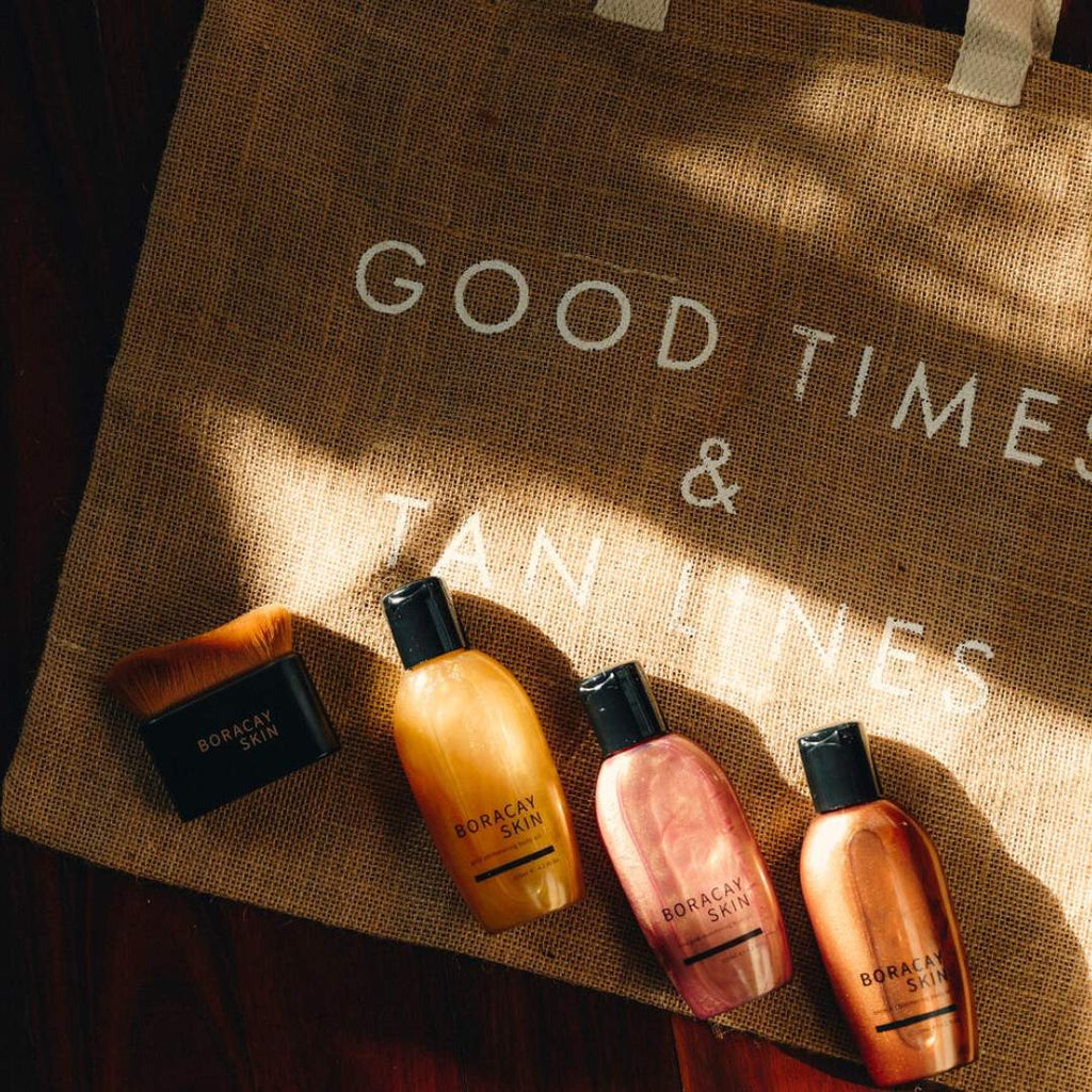 Boracay Skin Glow Getter Bundle products of 3 shimmering body oils and kabuki body brush arranged on a jute beach tote bag